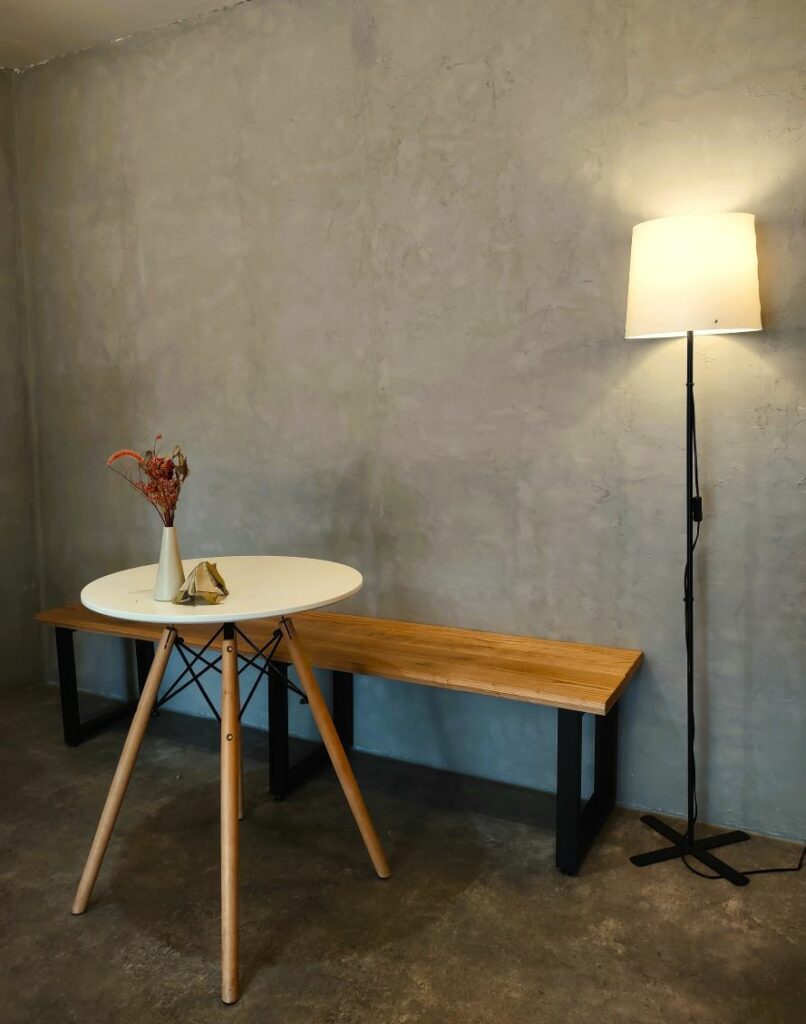 Cafe furniture. A coffee table in front of a bench, with a floor lamp next to them.
